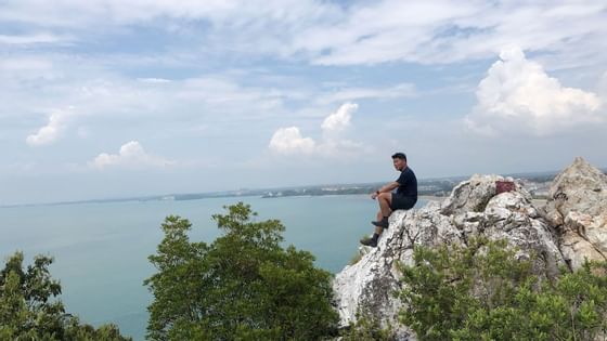 man sitting on rock at bukit batu putih of tanjung tuan port dic