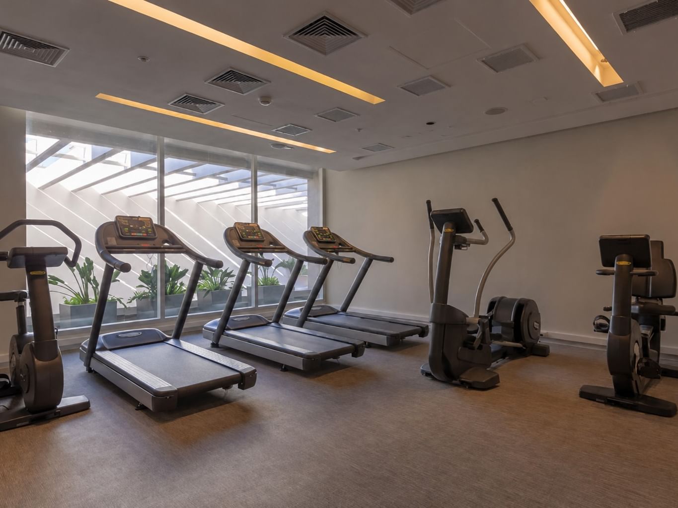 Centro fitness con cintas profesionales y bicicletas estáticas junto a ventanas en Veranda Hotel
