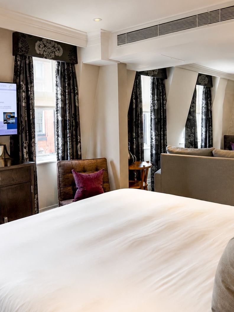 Elegant Townhouse Junior Suite with king bed, couch, and two smart TVs at The Capital Hotel in London.