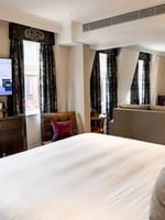 Elegant Townhouse Junior Suite with king bed, couch, and two smart TVs at The Capital Hotel in London.