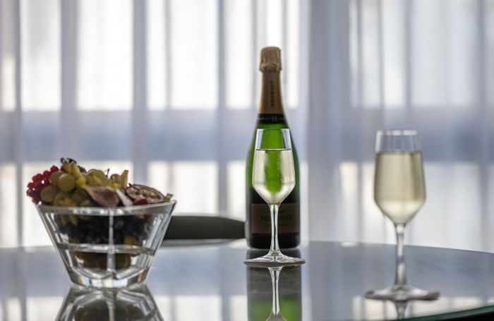 Two glasses and a bottle of champagne beside a fruit bowl at Warwick Reine Astrid - Lyon