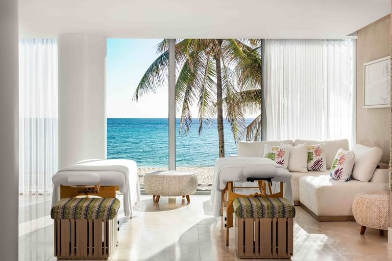 Interior of a suite at The Diplomat Resort featuring massage tables and a stunning ocean view through large windows