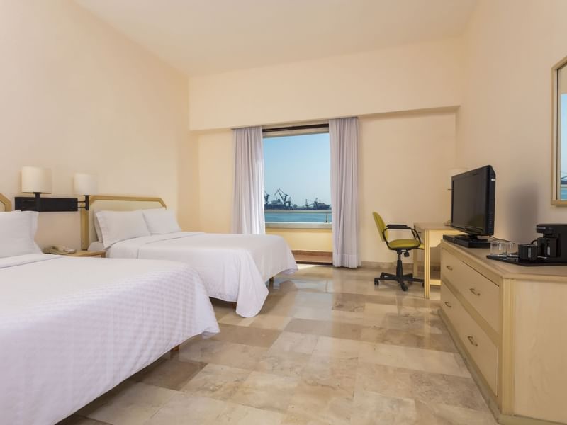 TV & work desk facing double beds in a bedroom at Fiesta Inn Hotels