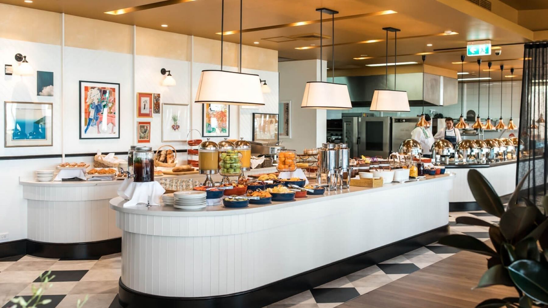 Breakfast at Elysium Manly with a long counter by juices under pendant lamps surrounding a black-and-white tiled floor
