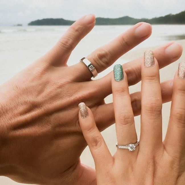 Photo of couples hands with wedding rings on the beach featuring our article on 