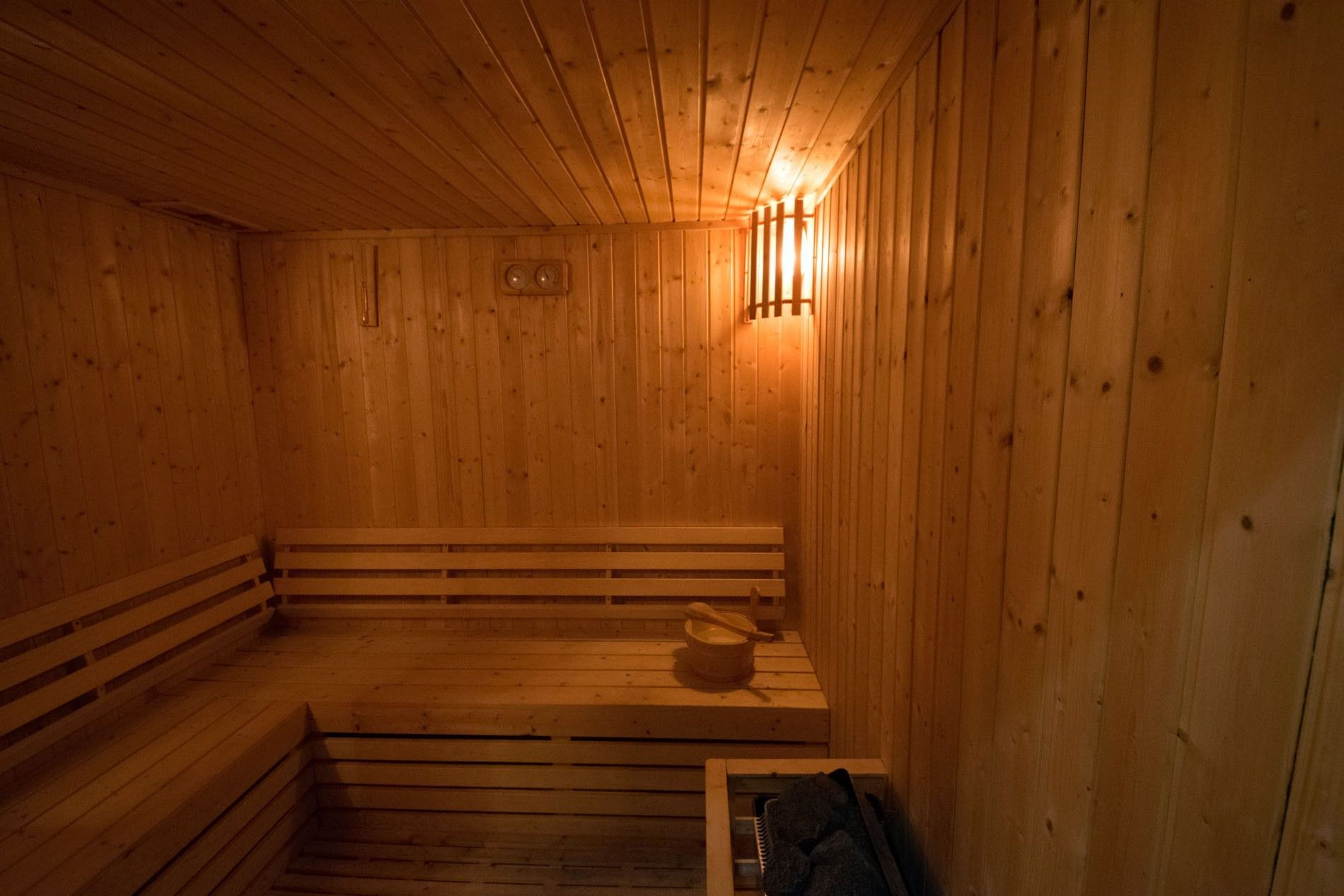 L-shaped wooden benches by a traditional bucket under warm ambient lighting at Warwick Doha Hotel