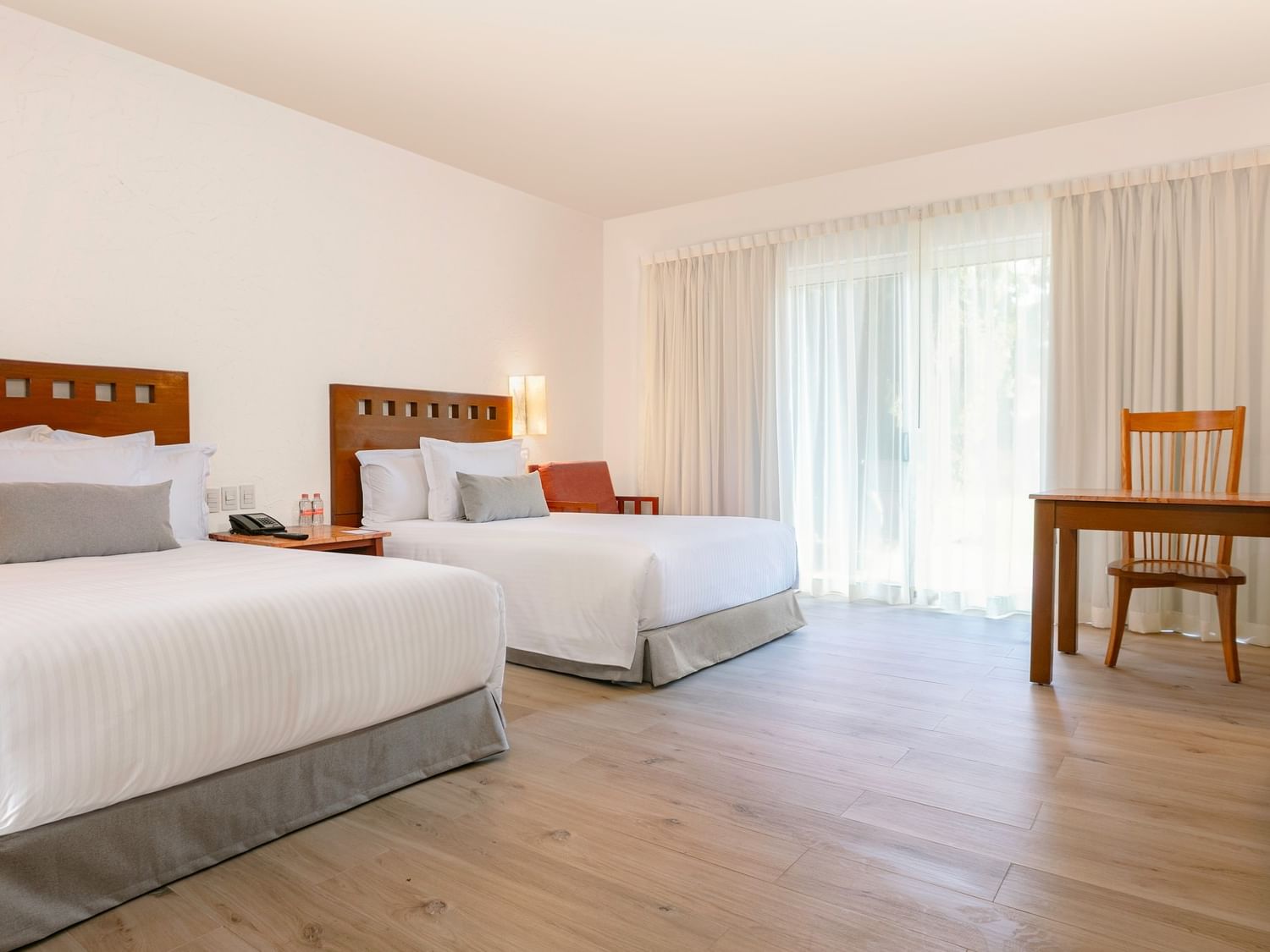 Two double beds, a desk, and a dresser in a room at Camino Real Guadalajara in Zapopan