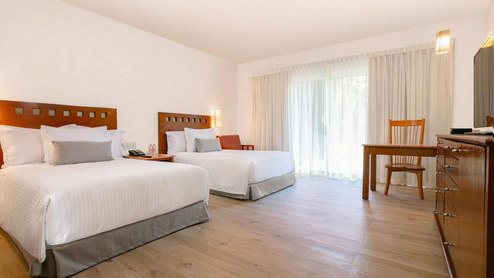 Two double beds, a desk, and a dresser in a room at Camino Real Guadalajara in Zapopan