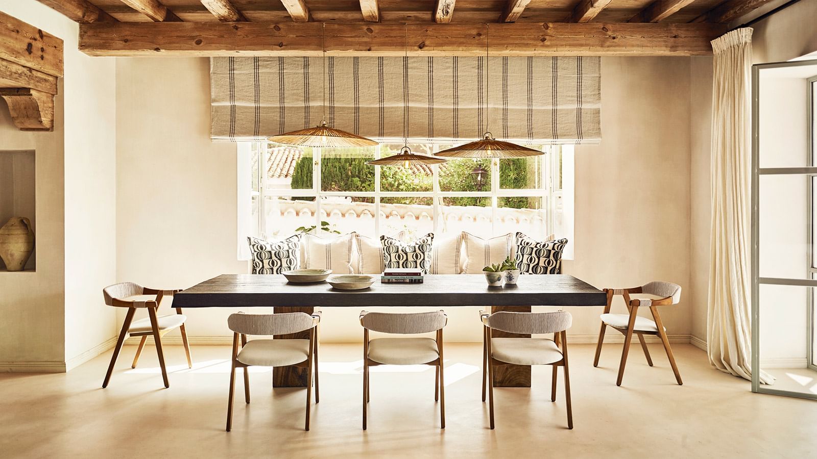 Dining room with a long dark wood table placed under woven light fixtures near a large window at the Marbella Club