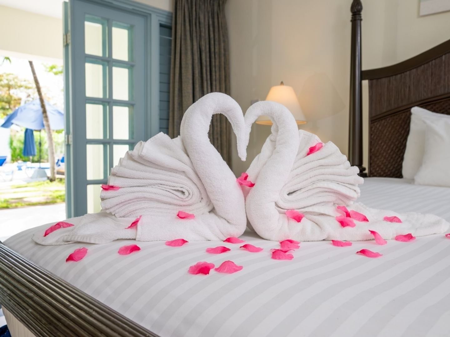 Two swan-shaped towels with petals on a bed at Savannah Beach Hotel.