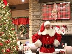 santa smiling next to lit up tree
