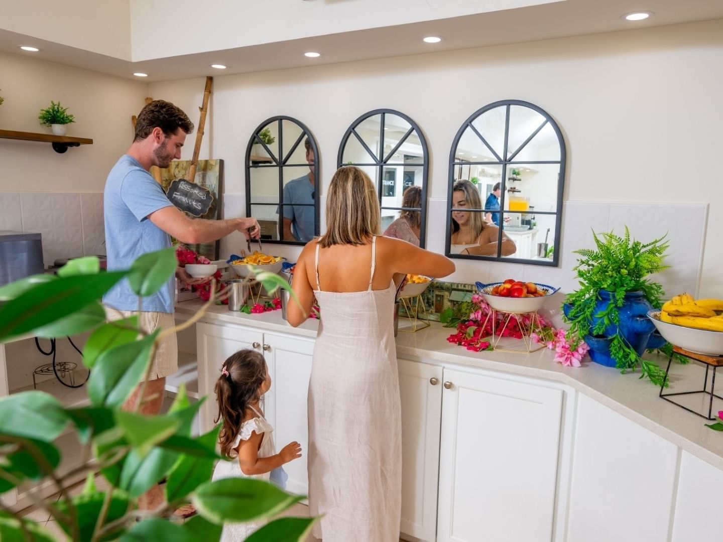 A family picking fruit at a buffet with tropical decor and plants at Savannah Beach Hotel.