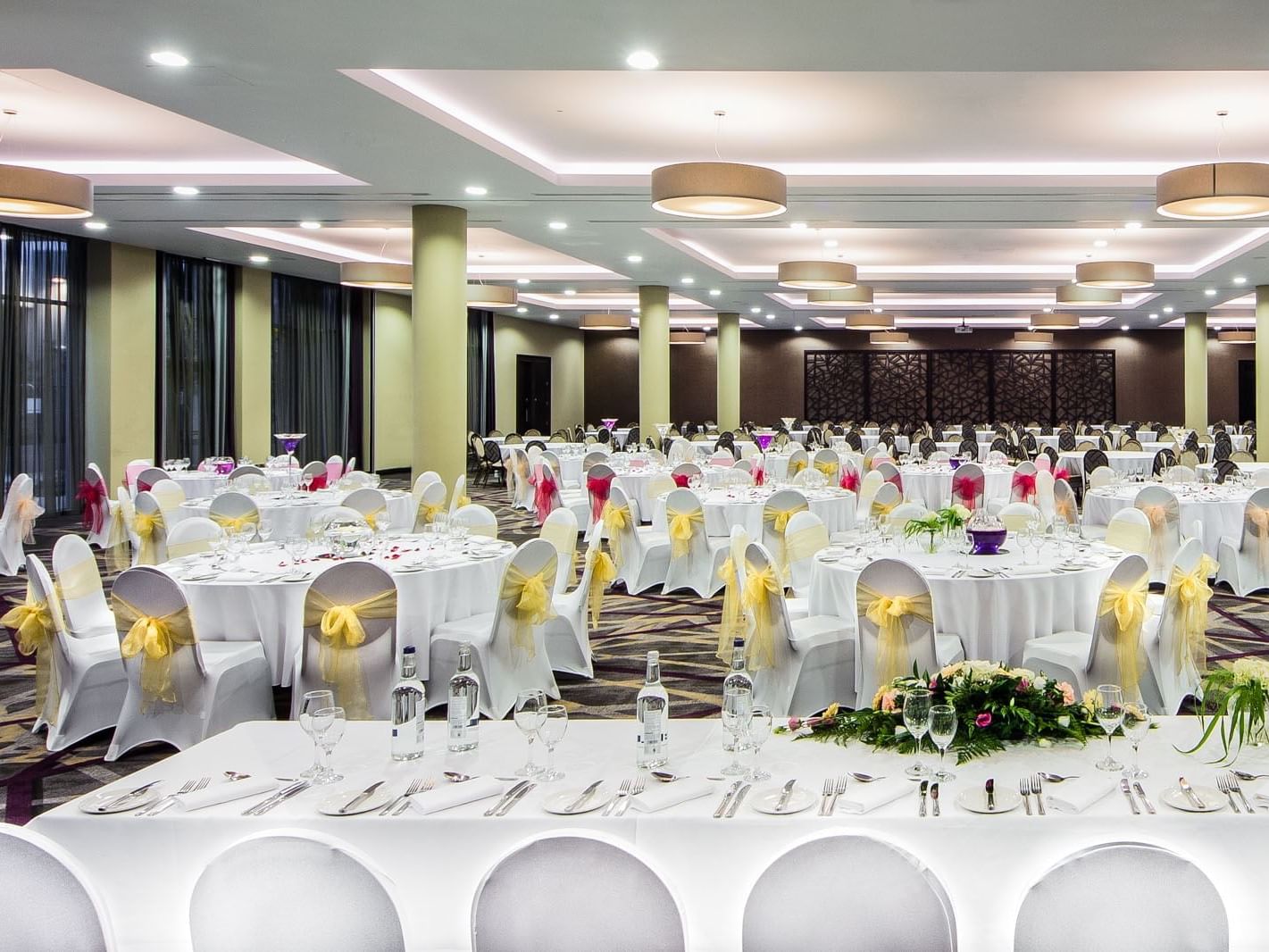 Stylish banquet hall with round tables adorned with colorful sashes and fine dining tableware at Heston Hyde Hotel