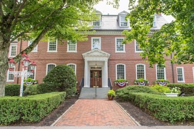 Brick path leading to the classic red brick entrance of The Exeter Inn, surrounded by lush greenery