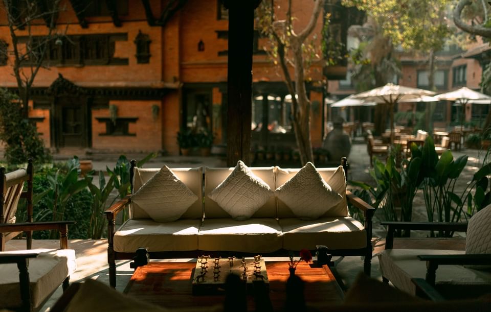 Outdoor seating area featuring comfy chairs with flush cushions, in front of a brick building at Dwarika's Hotel Kathmandu