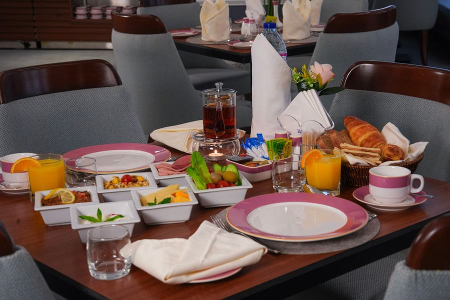 Breakfast table set with various food items, drinks, and napkins at Warwick Hotel & Spa - Jeddah.