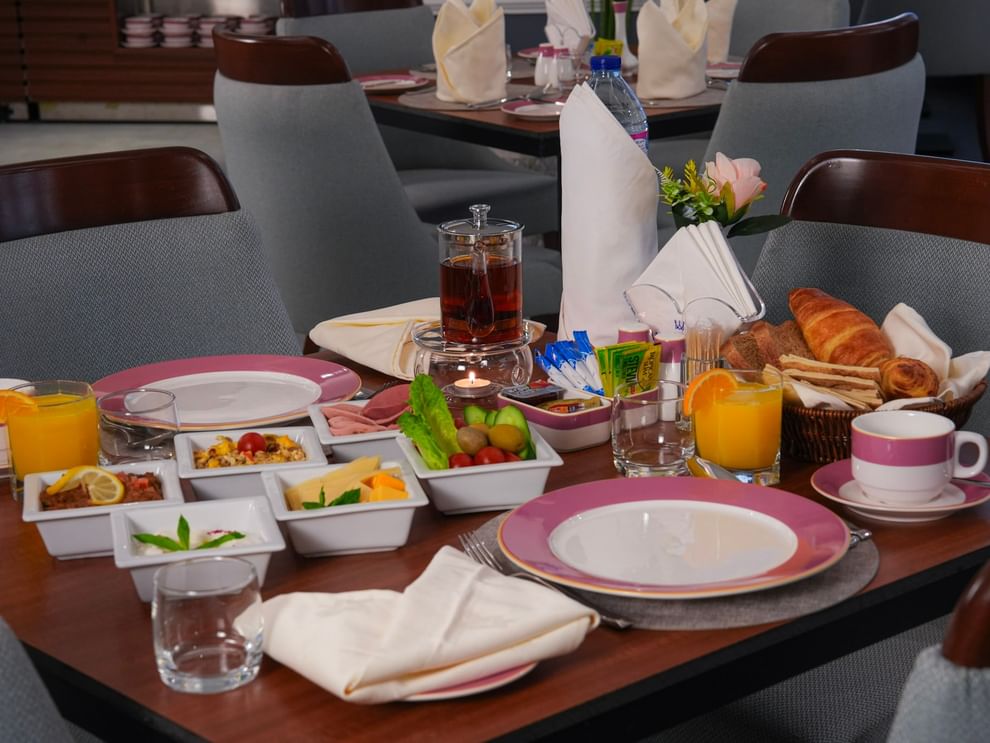 Breakfast table with various dishes, bread, and drinks at Warwick Hotel & Spa - Jeddah.
