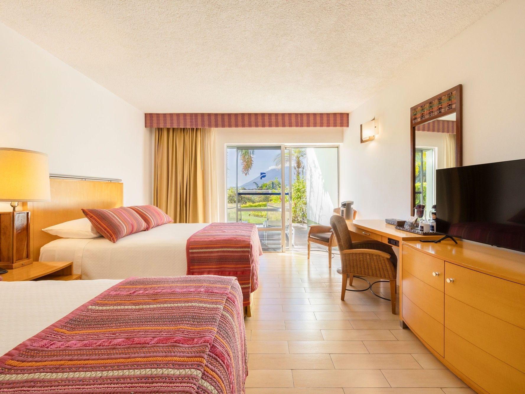 Garden Accessible Room with two beds, colorful striped bedding, and patio access at Porta Hotel del Lago, Panajachel.
