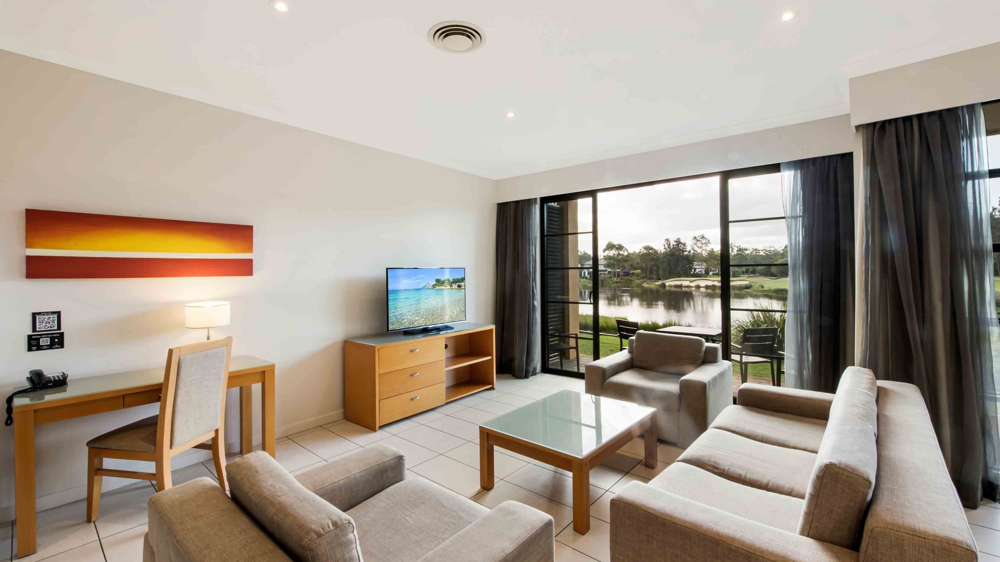 Two Bedroom Apartment living room with sofas, TV, and garden view through sliding doors at Mercure Kooindah Waters
