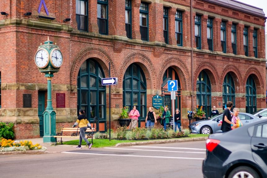 Pedestrians walking on a sidewalk by a historic clock at Rodd Charlottetown Hotel, one of the best hotel in PEI