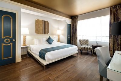 Upscale Deluxe One-Bedroom King Suite at Riviera Hotel South Beach with a king bed, armchair, and gold ceiling accents