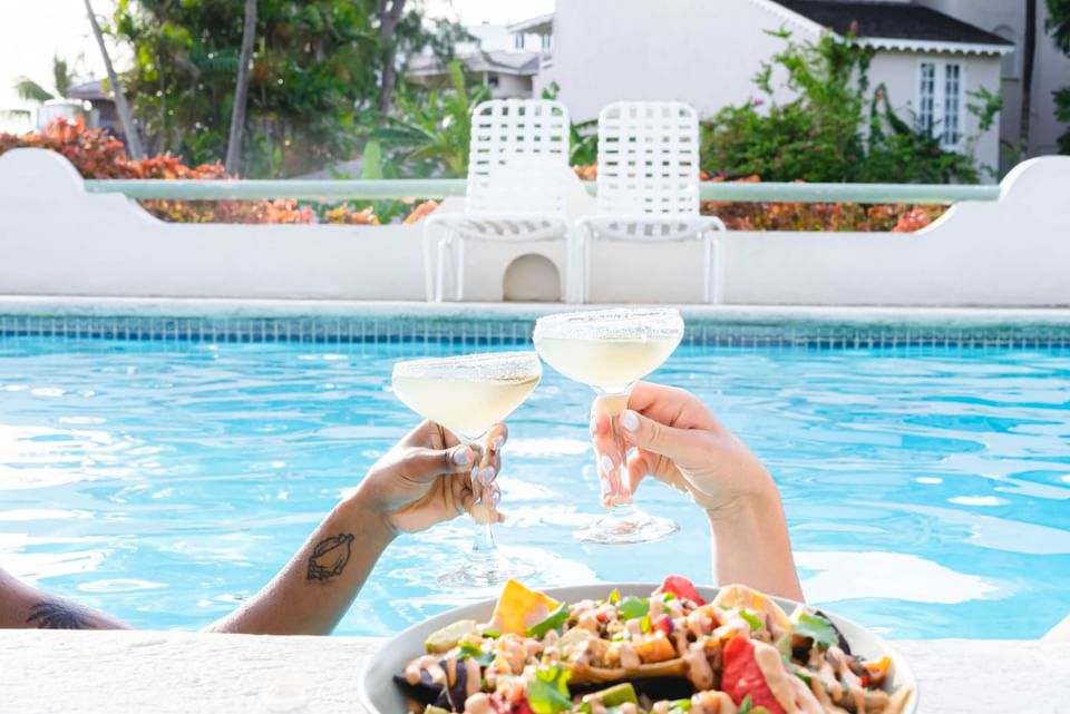 Couple toasting cocktails by a pool at Bougainvillea Barbados