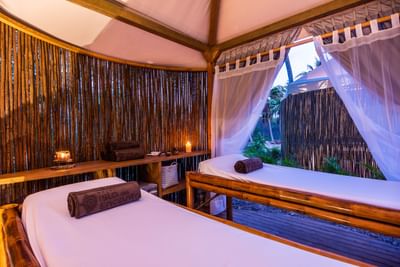 Two spa beds in a cozy bamboo hut with candles in spa at Hotel Isla Del Encanto