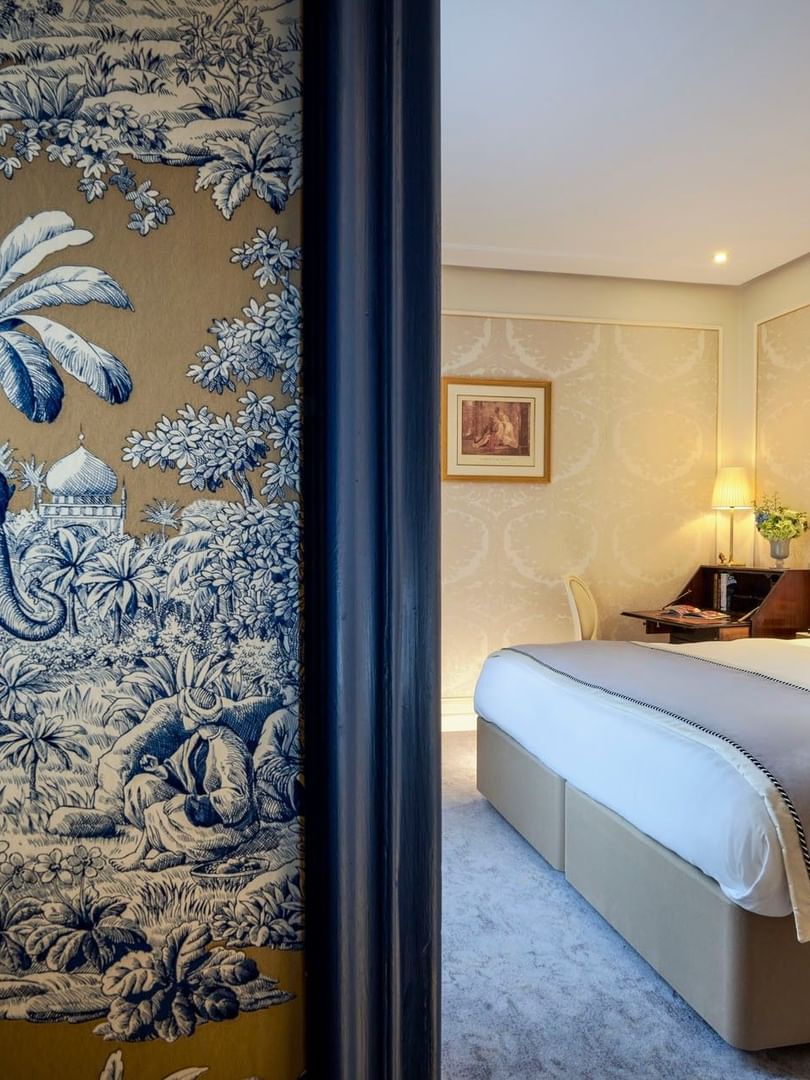 Élégante chambre Deluxe avec un grand lit, du papier peint à motifs et une vue sur Paris à l'Hôtel Westminster - Paris.