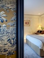 Élégante chambre Deluxe avec un grand lit, du papier peint à motifs et une vue sur Paris à l'Hôtel Westminster - Paris.