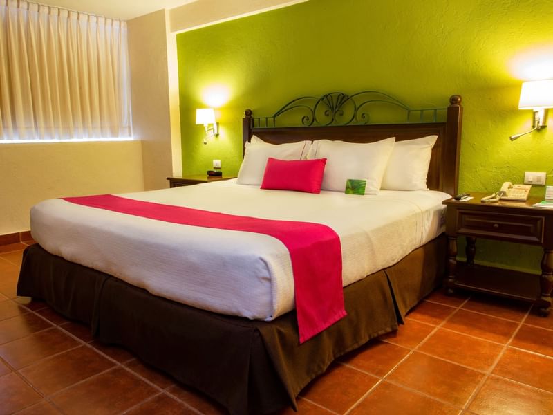 King bed and wall lamps in Superior King Room at Gamma Hotels