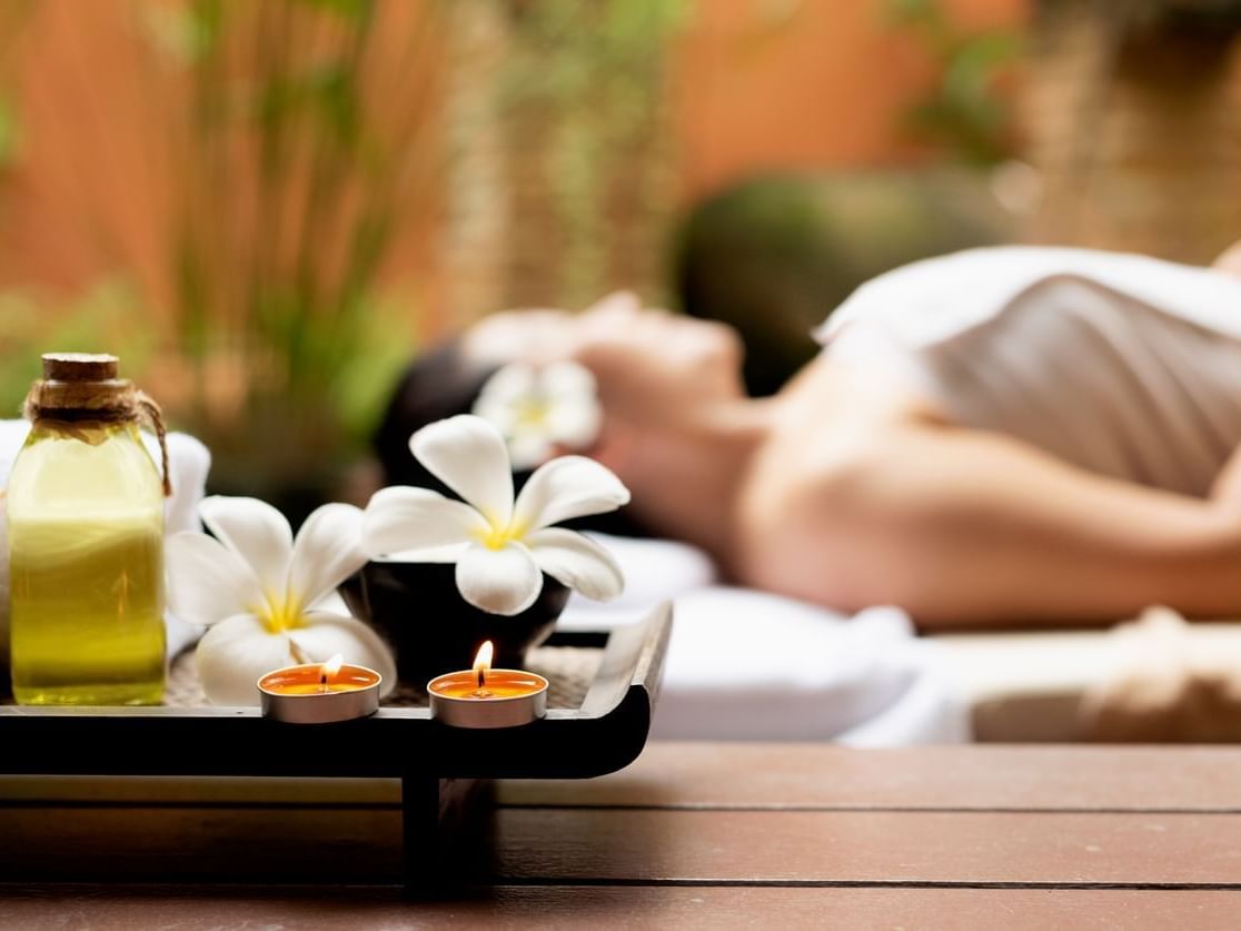 Spa items & a lady lying down on a massage bed at Grand Coloane