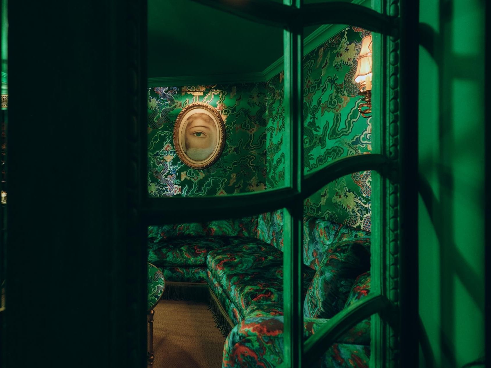 Green room with ornate couch and framed artwork at Petit Ermitage West Hollywood.
