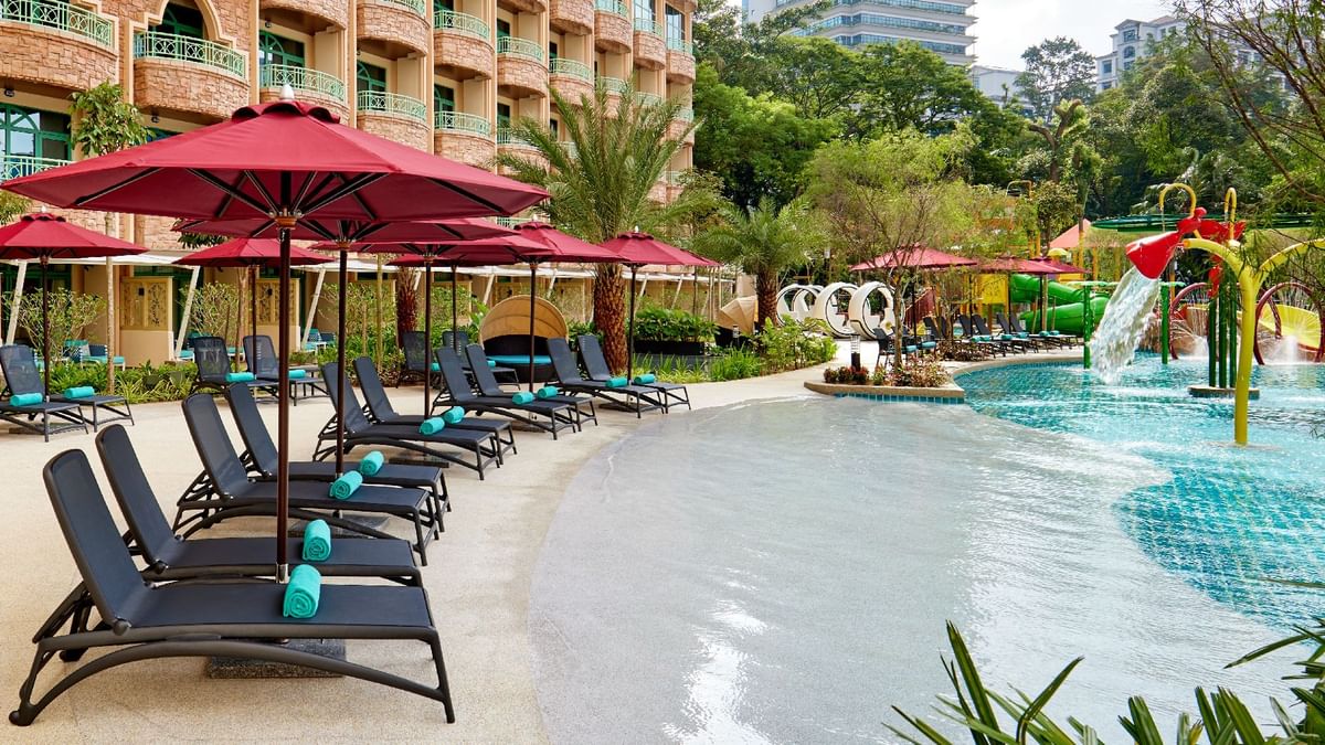 Peaceful poolside setting with red umbrellas and comfortable sun loungers at Sunway Resort