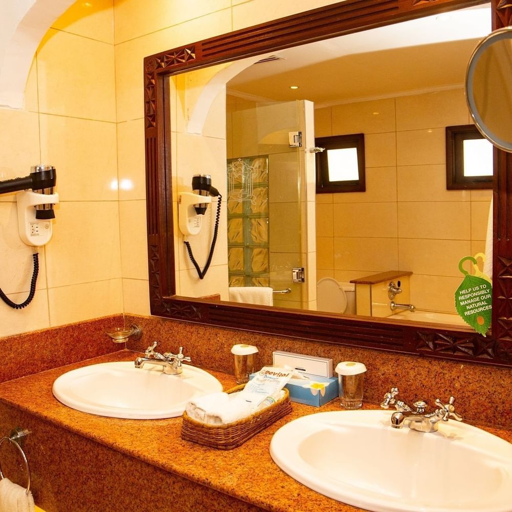Two sinks with toiletries and mirror in bathroom at Serena Beach Resort & Spa Mombasa.