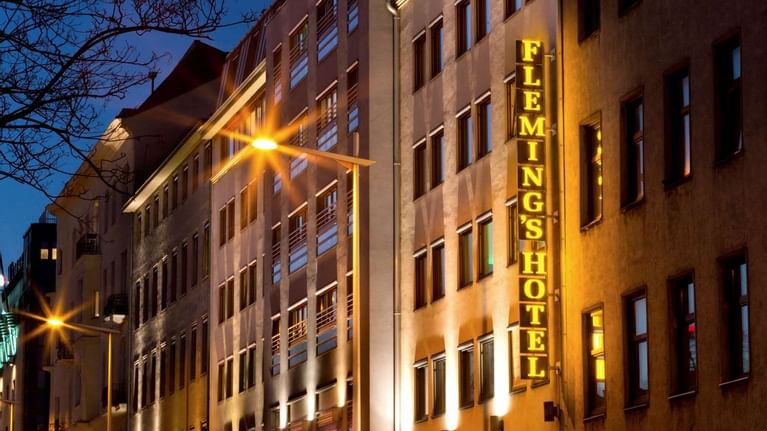 Street view of Flemings Conference Hotel Wien at dusk, with warm lighting highlighting the building's facade