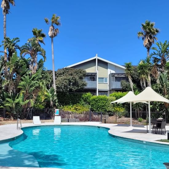 Stunning crystal blue lagoon pool with large white umbrellas at Pullman Magenta Shores