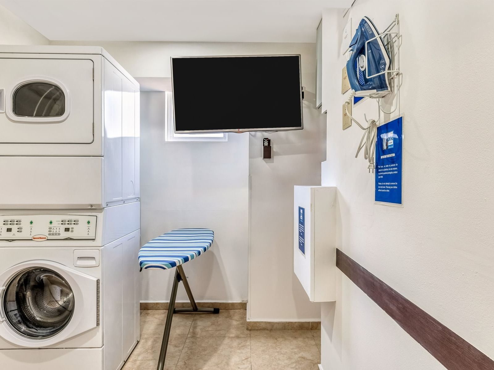 A laundry room with a stacked washer, dryer, and iron board at One Hotels