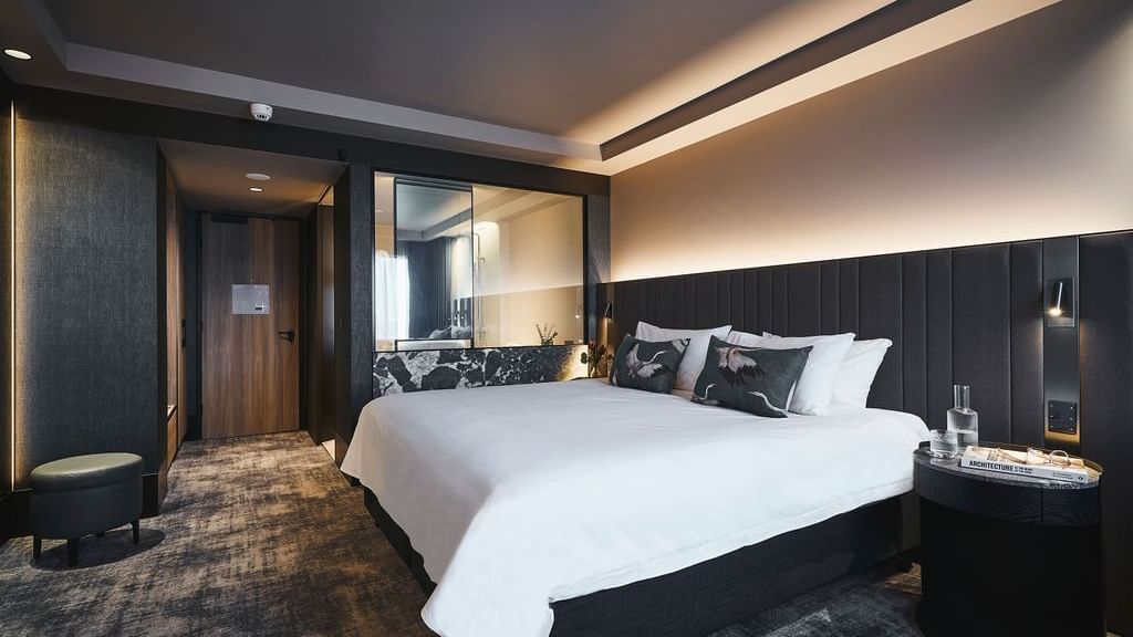 Modern Deluxe Executive Room with king bed, dark wood paneling, and ambient lighting at Pullman East Melbourne.