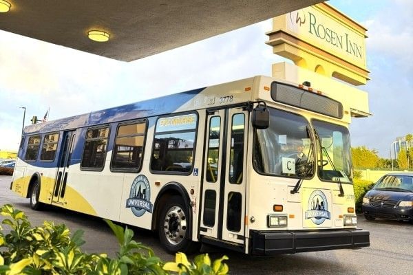 The Universal Partner Hotel theme park shuttle parked beside the Rosen Inn sign at the front of the hotel.