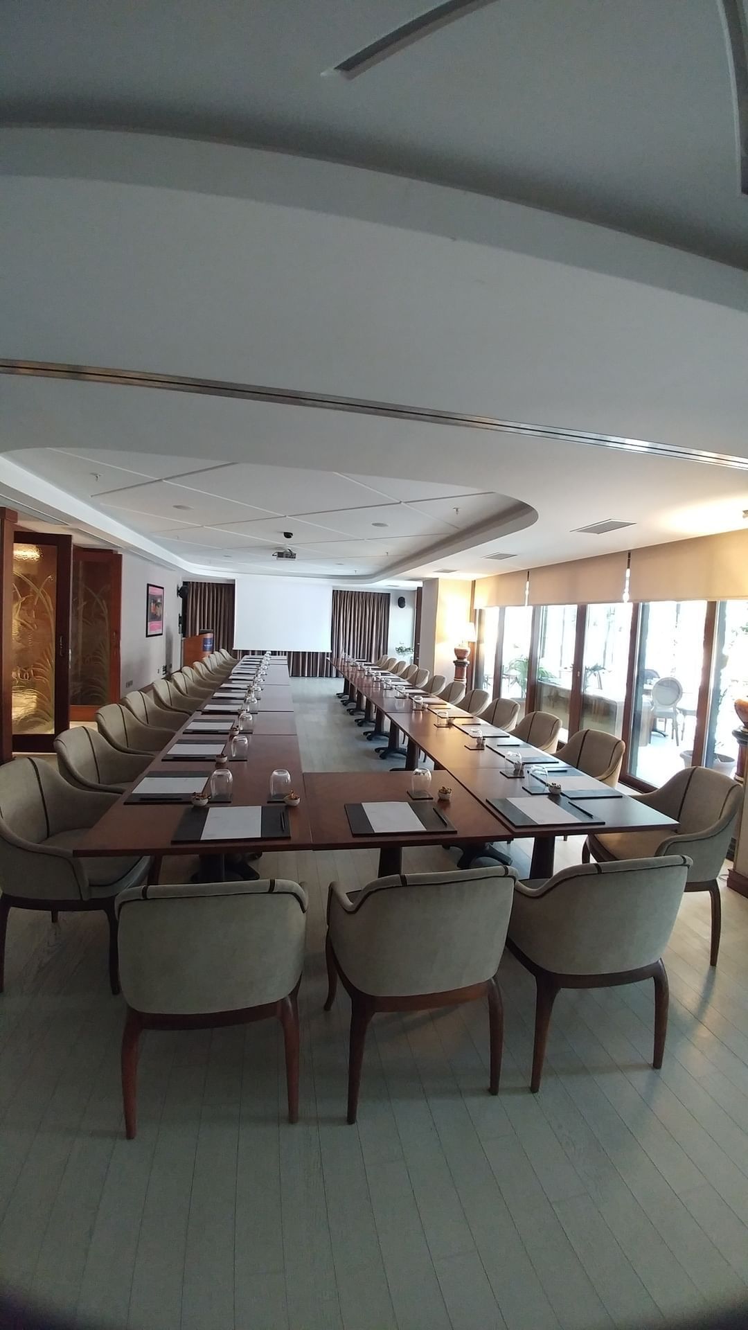 Row of chairs by a long table under a recessed ceiling near large windows in Kugu 2 Hall at Warwick Ankara