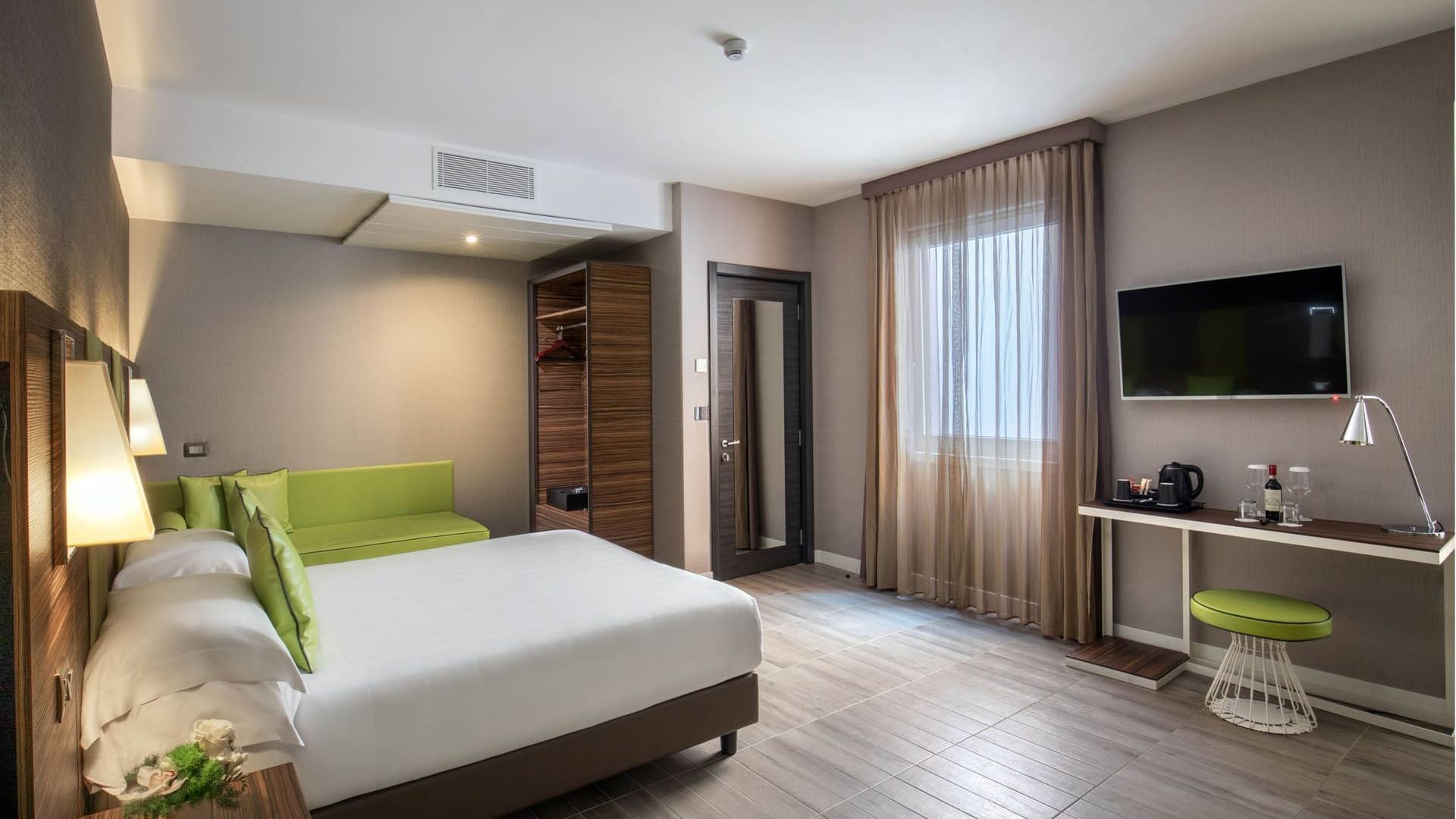 Large Family Room featuring a queen bed, seating area, wooden closet, TV, and desk with refreshments at The Republic Hotel