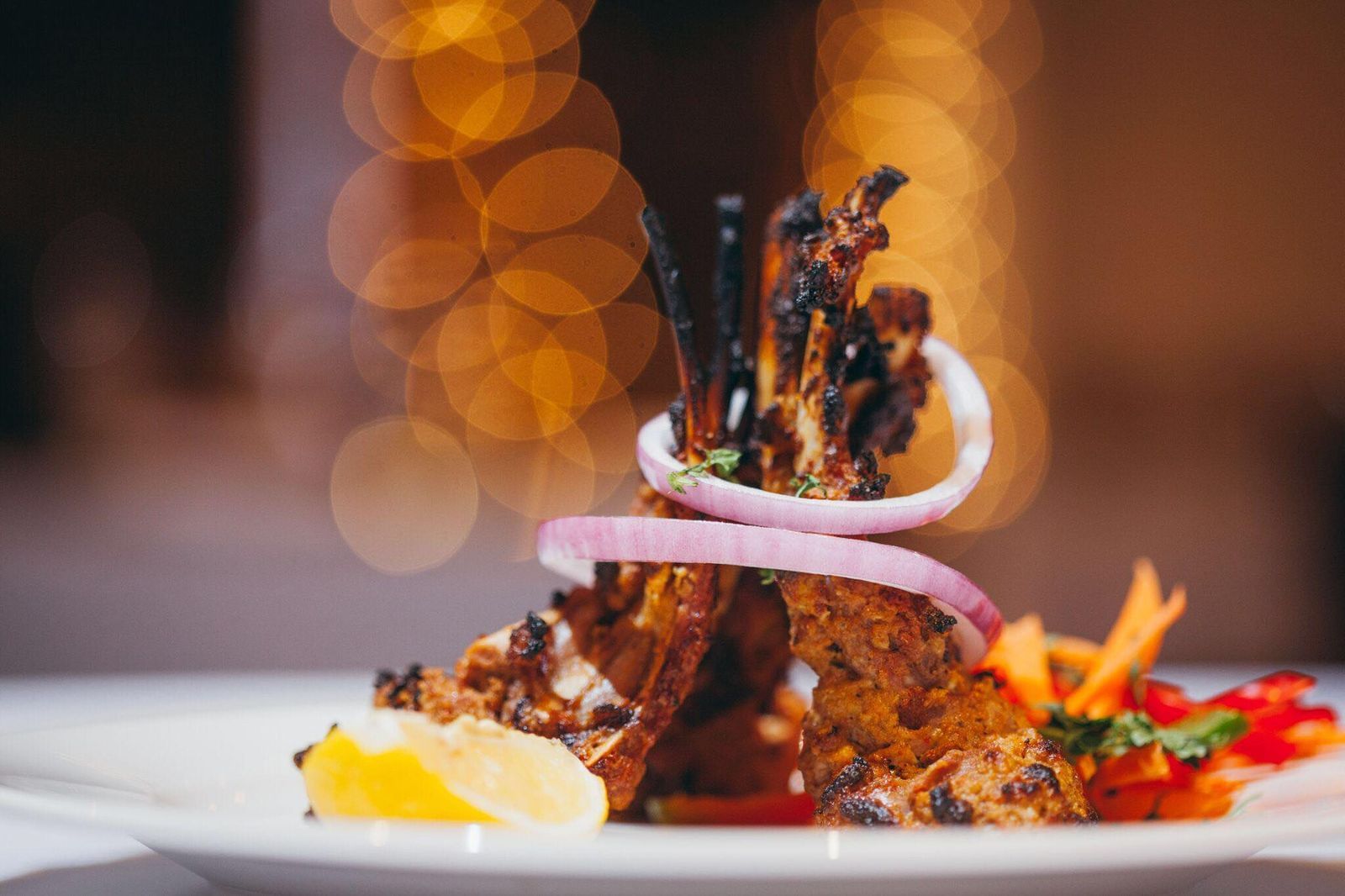 A plated dish of grilled meat with onions and vegetables.