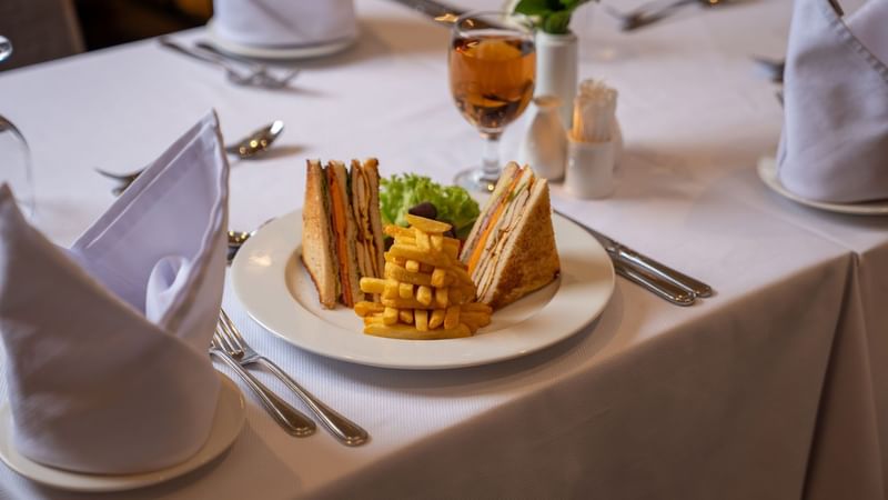 Plate with sandwich, fries, and a drink at Al Firdous at Saja by Warwick Madinah.