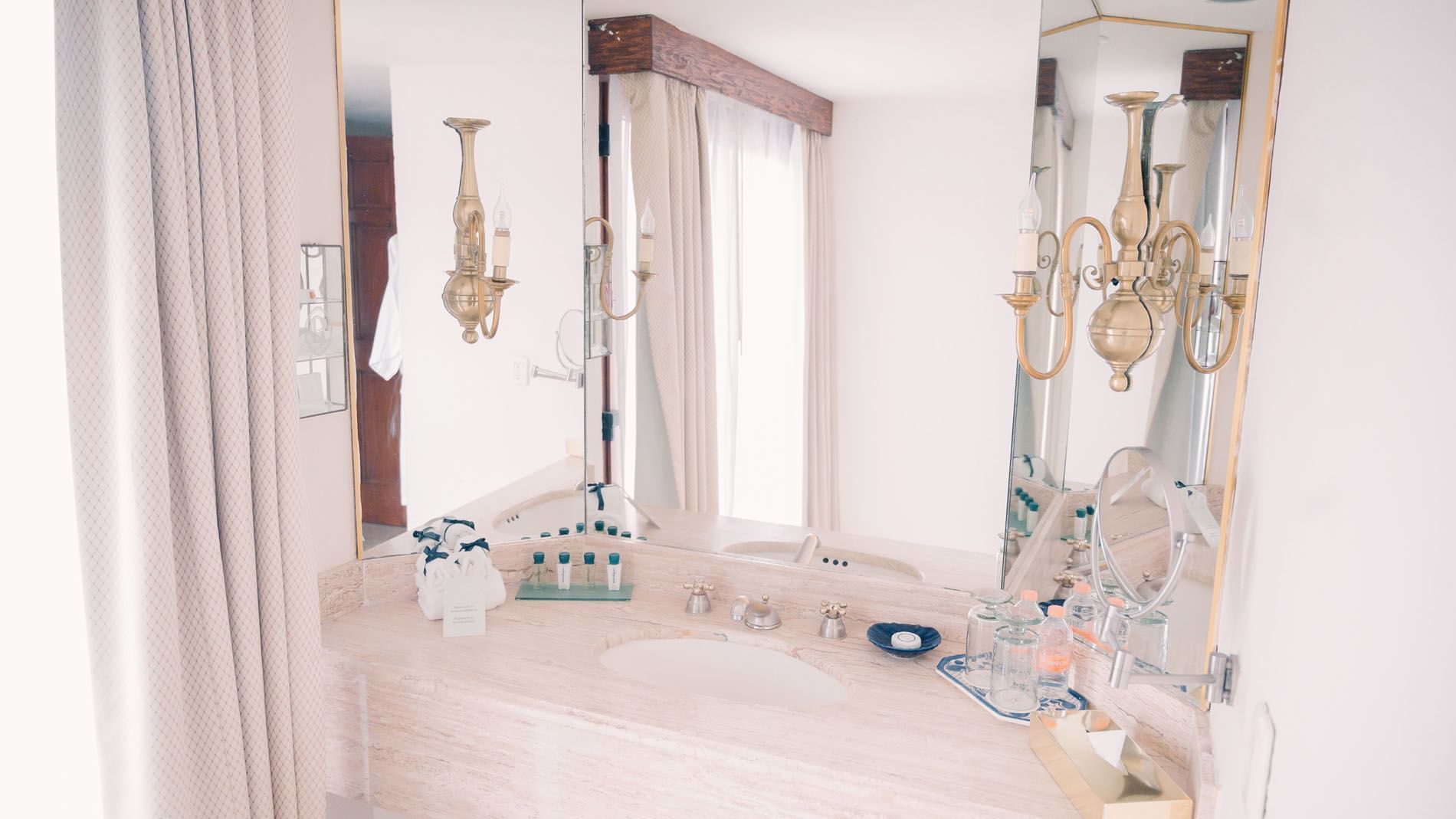 King Master Suite bathroom with a large mirror, white sink, and gold sconces at Quinta Real Zacatecas