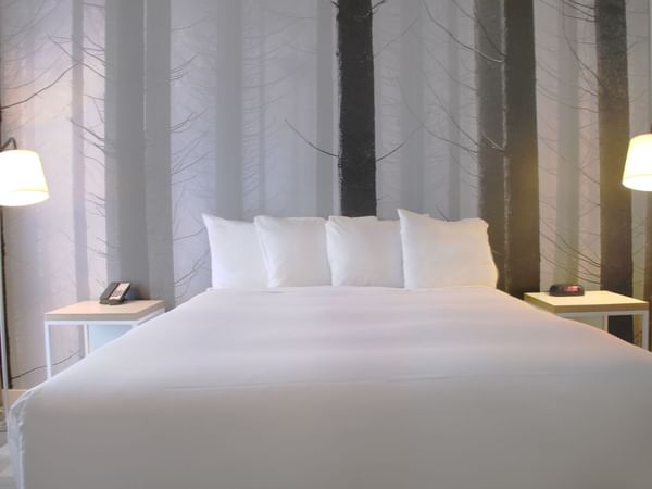Cozy bed in hotel room with artwork of pine trees