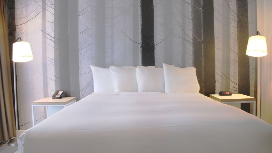 Cozy bed in hotel room with artwork of pine trees