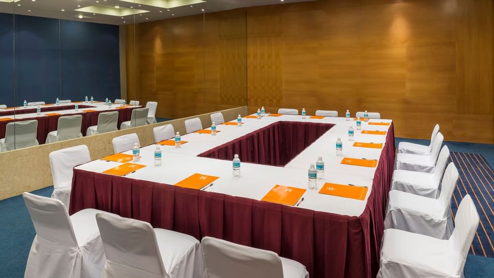 Conference table with orange folders and water bottles in the Budapest Venue at Real Inn San Luis Potosi