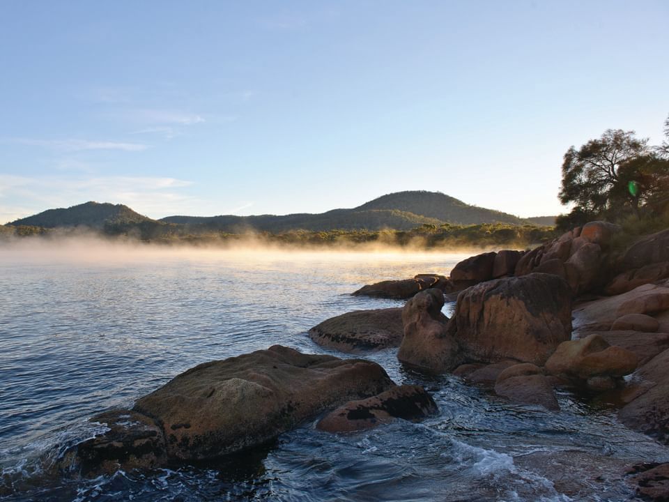 Scenic view of East Coast Cruises beach with large rocks near Freycinet Lodge