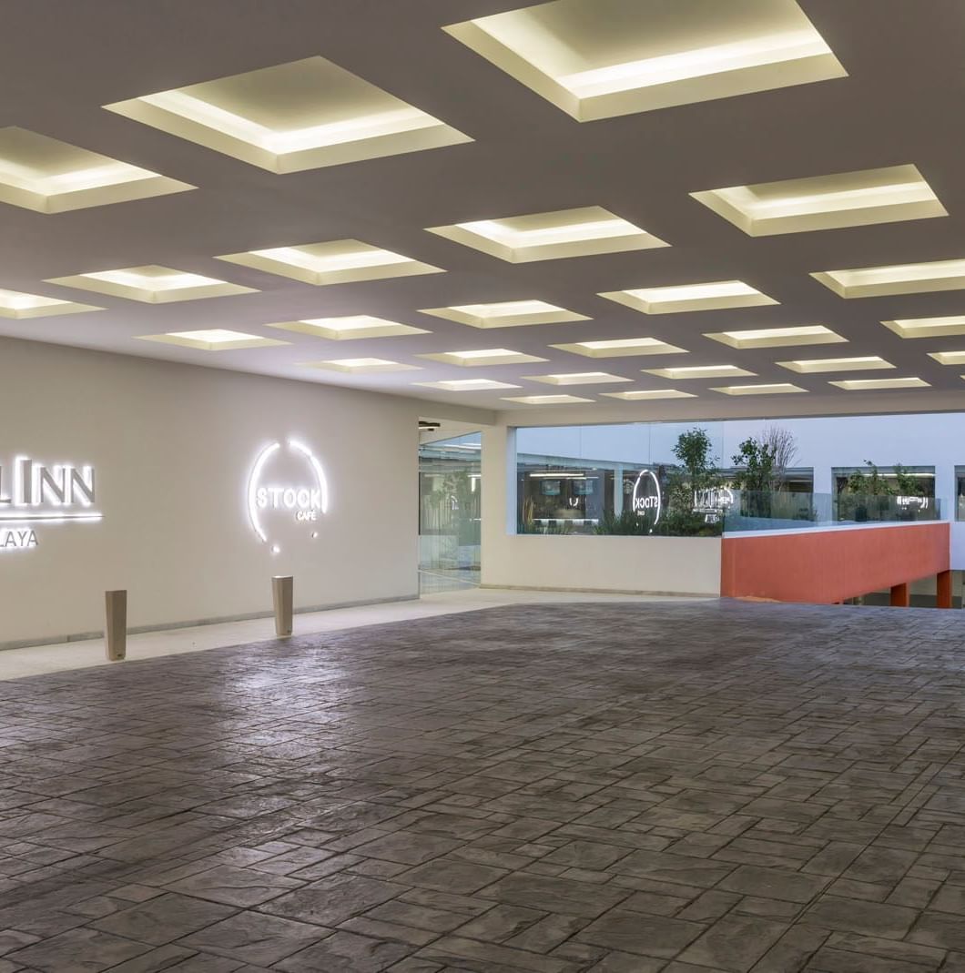 Glowing entrance sign featuring a recessed ceiling with a grid of bright square lights at Real Inn Celaya