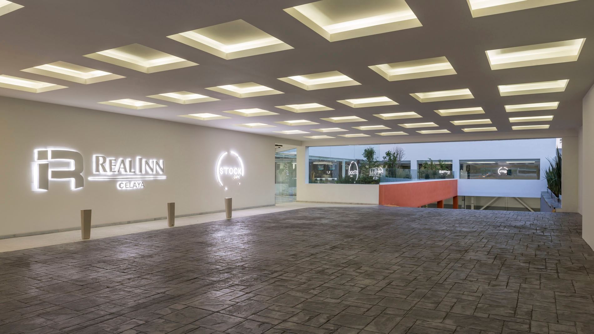 Glowing entrance sign featuring a recessed ceiling with a grid of bright square lights at Real Inn Celaya